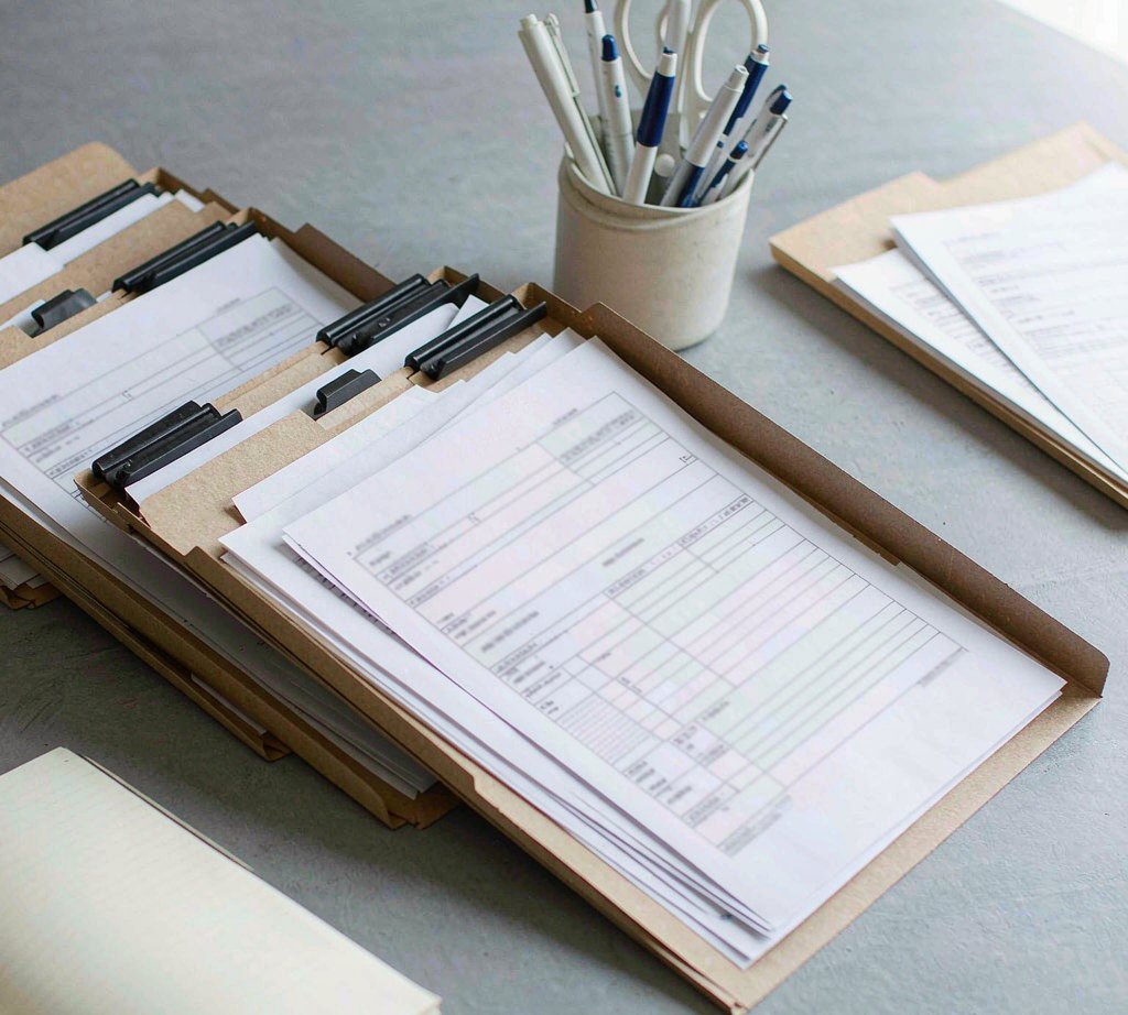 A compliance folder with document wallets and blank forms
