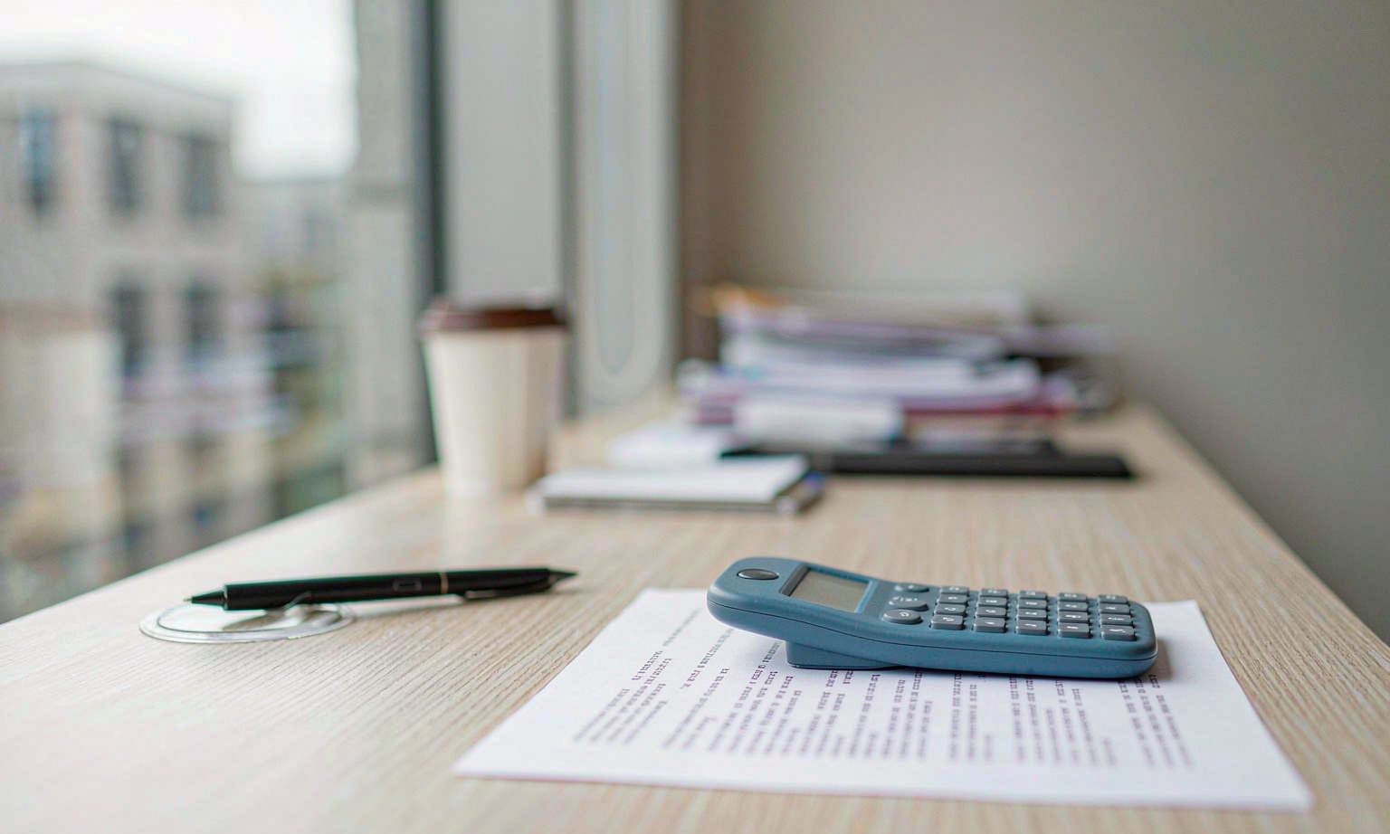 A printed tenancy fee schedule beside a calculator on a letting agent's desk
